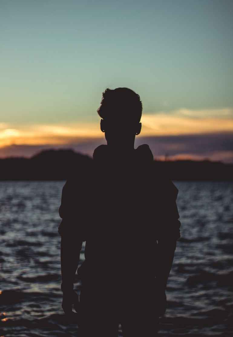 silhouette photo of person near body of water